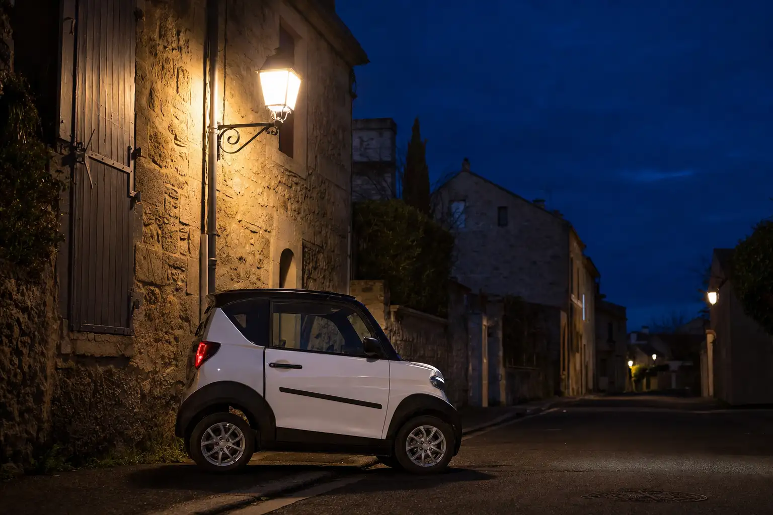 Voiture sans permis stationnée de nuit dans une rue éclairée par un lampadaire, antivol visible sur le volant