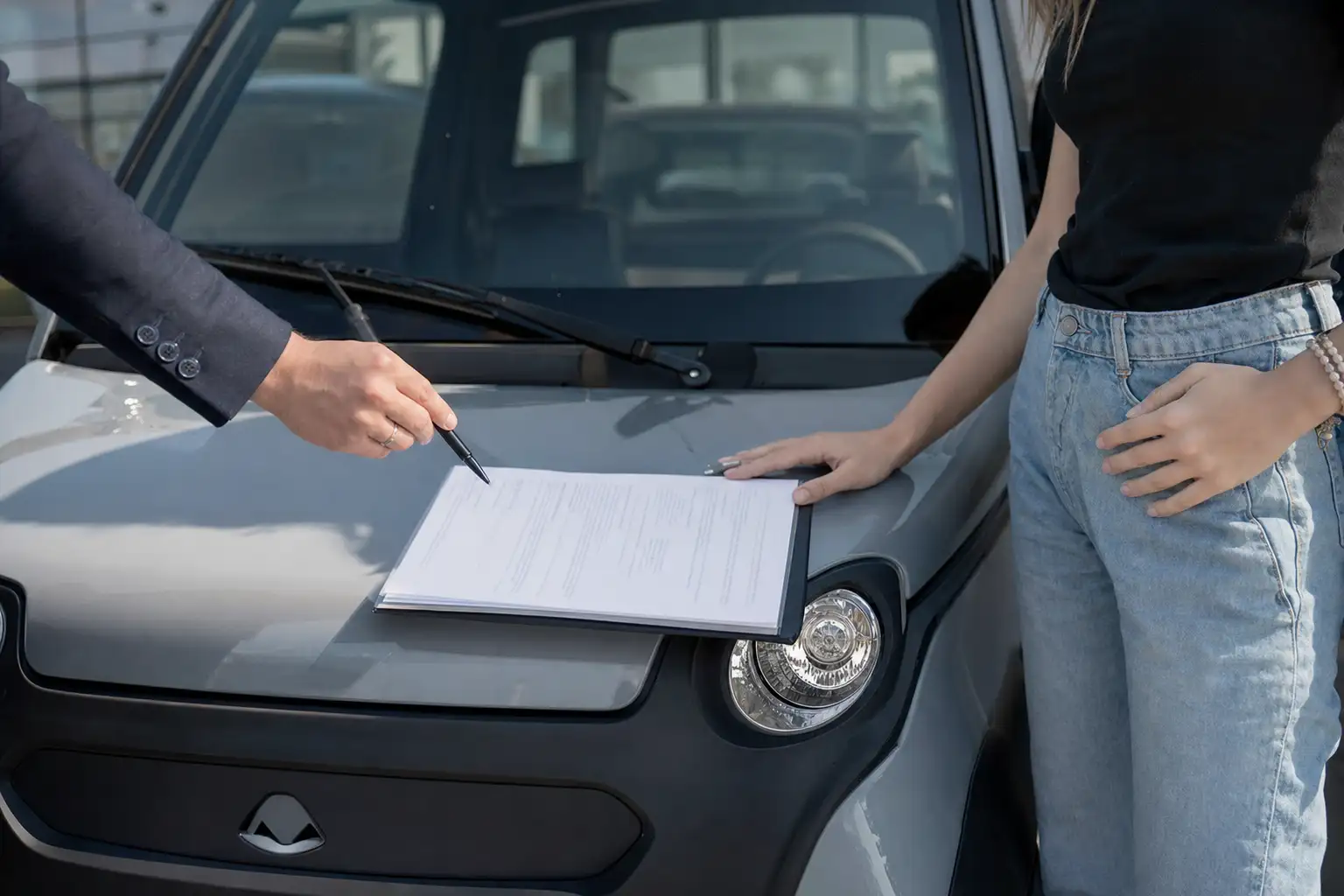 Trois voitures sans permis alignées devant une concession, du modèle d'occasion au modèle neuf
