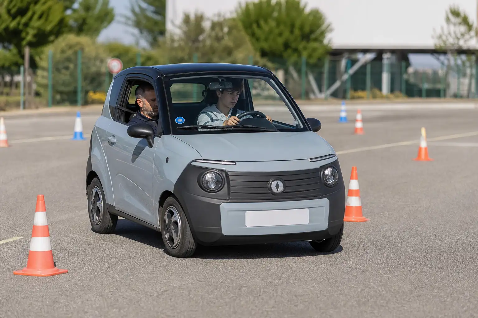 Adolescent au volant d'une voiture sans permis d'apprentissage sur un plateau d'auto-école, moniteur assis à côté donnant des instructions