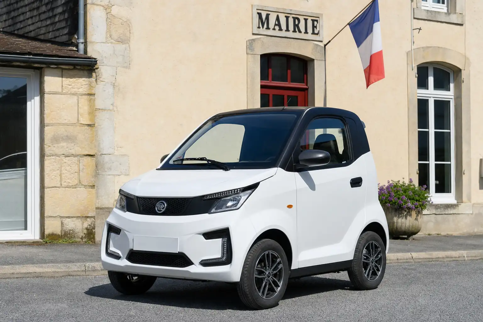 Petite voiture sans permis blanche vue de trois quarts, stationnée sur une place de village française