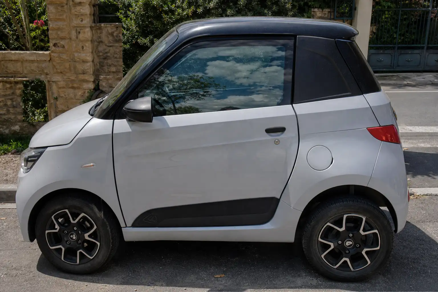 Vitre avant d'une voiture sans permis moderne légèrement teintée, reflet du ciel visible, gros plan sur la portière conducteur
