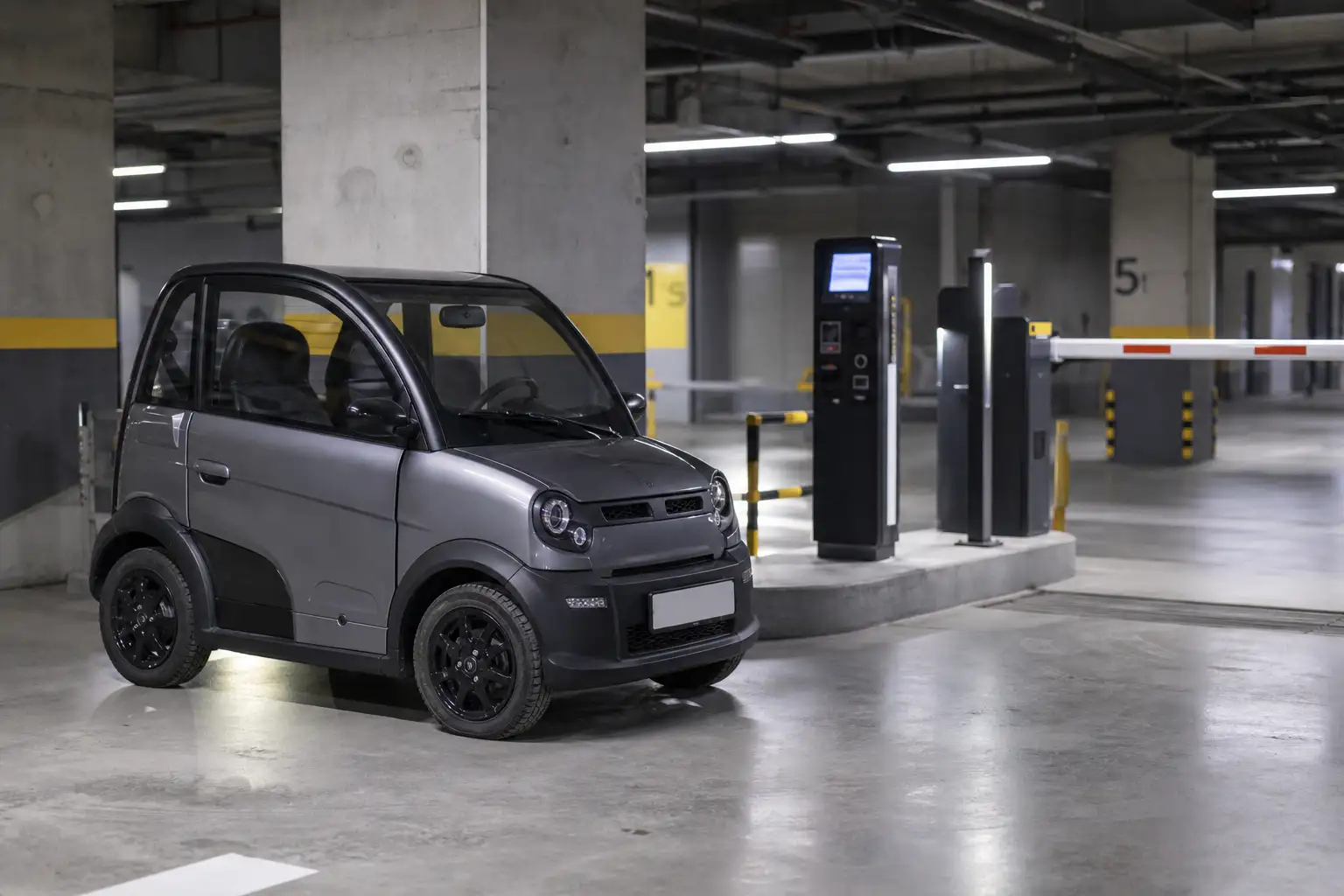 Voiture sans permis garée dans un parking souterrain payant, éclairage artificiel, barrières automatiques visibles en arrière-plan