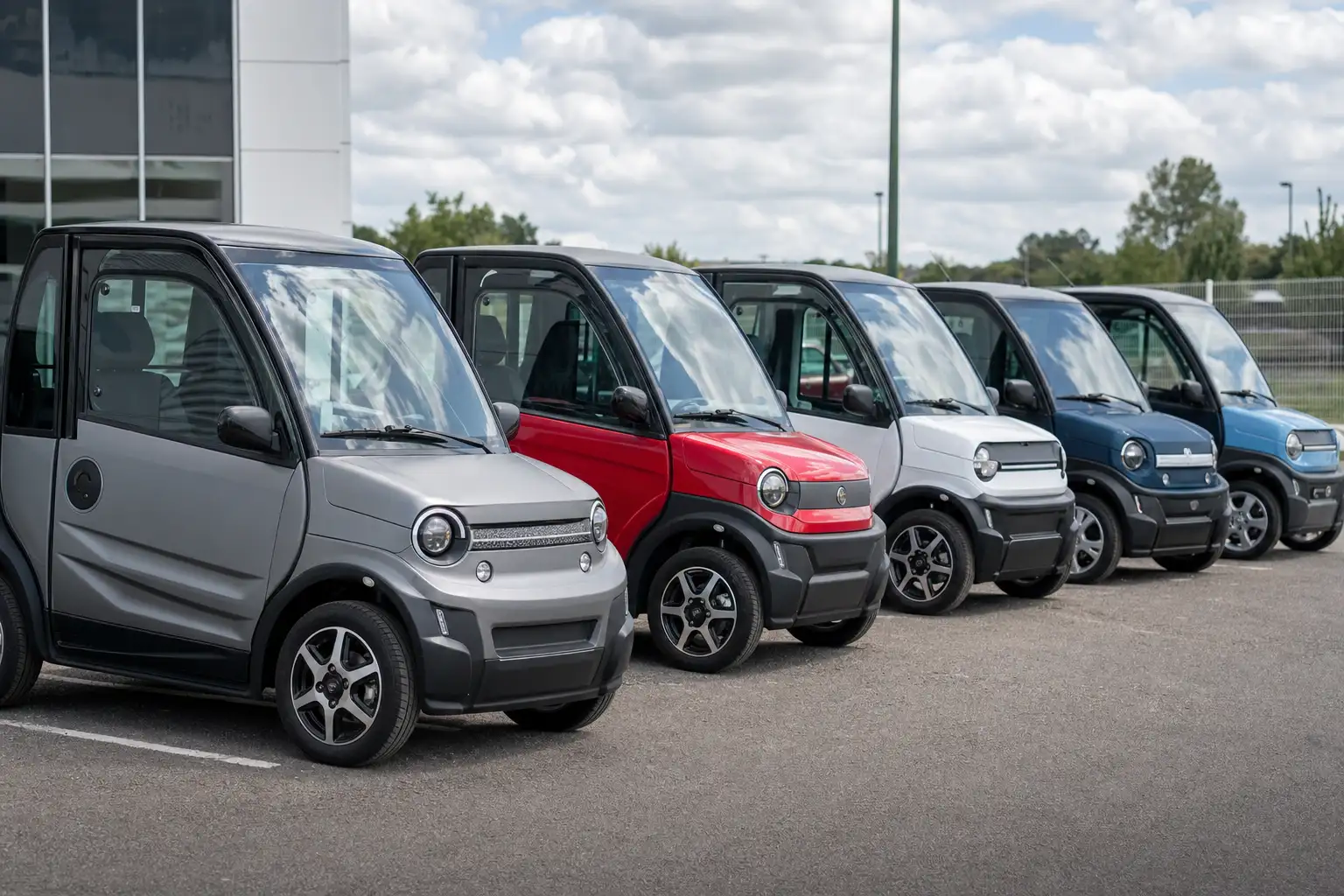 Voitures sans permis de plusieurs marques alignées sur le parking d'un concessionnaire, vues de face